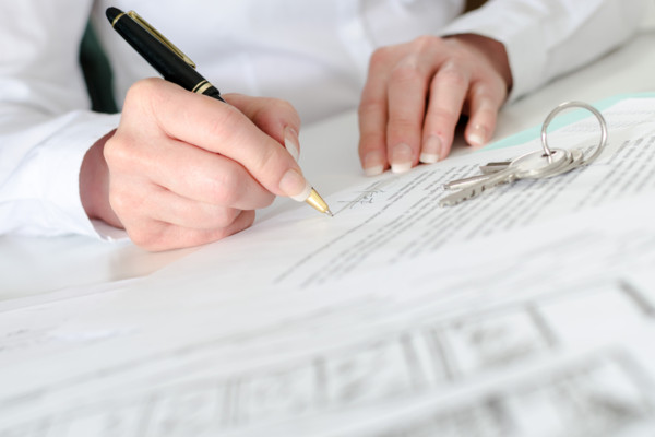 Client signing a real estate contract in real estate agency