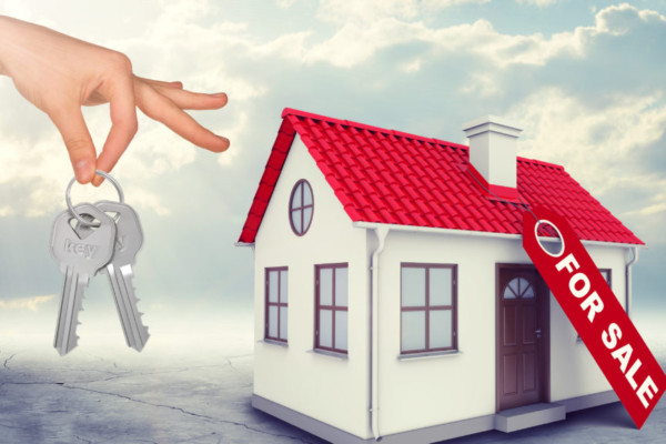 House for sale with hand holding keys on blue sky background
